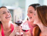 Group of friends laughing over glasses of wine